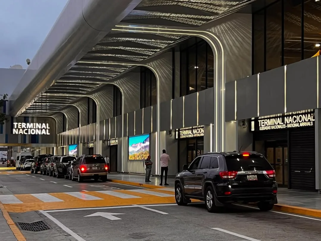 Acceso principal de la Terminal Nacional del Aeropuerto Internacional de Maiquetía, mostrando la fachada modernizada, su iluminación y el flujo vehicular en la zona de llegadas nacionales.