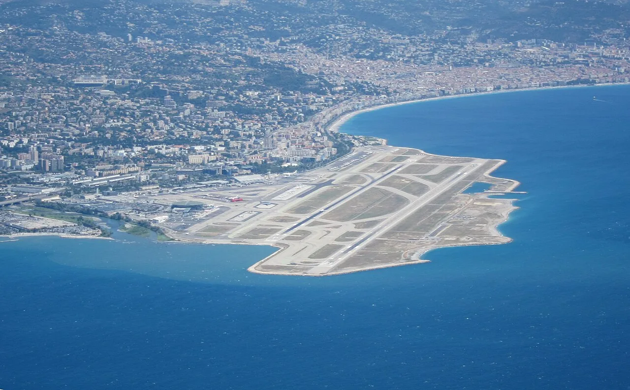 Nice-Côte d’Azur airport (NCE / LFMN) seen from the sky, looking in the north-east direction. The mouth of the Var is seen on the left, and Nice is visible in the background.